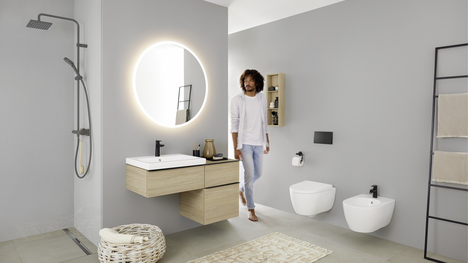 En man går in i ett badrum med tvättställ, WC, bidé och badrumsmöbler från Geberit iCon badrumsserie En man går in i ett badrum med tvättställ, WC, bidé och badrumsmöbler från Geberit iCon badrumsserie
