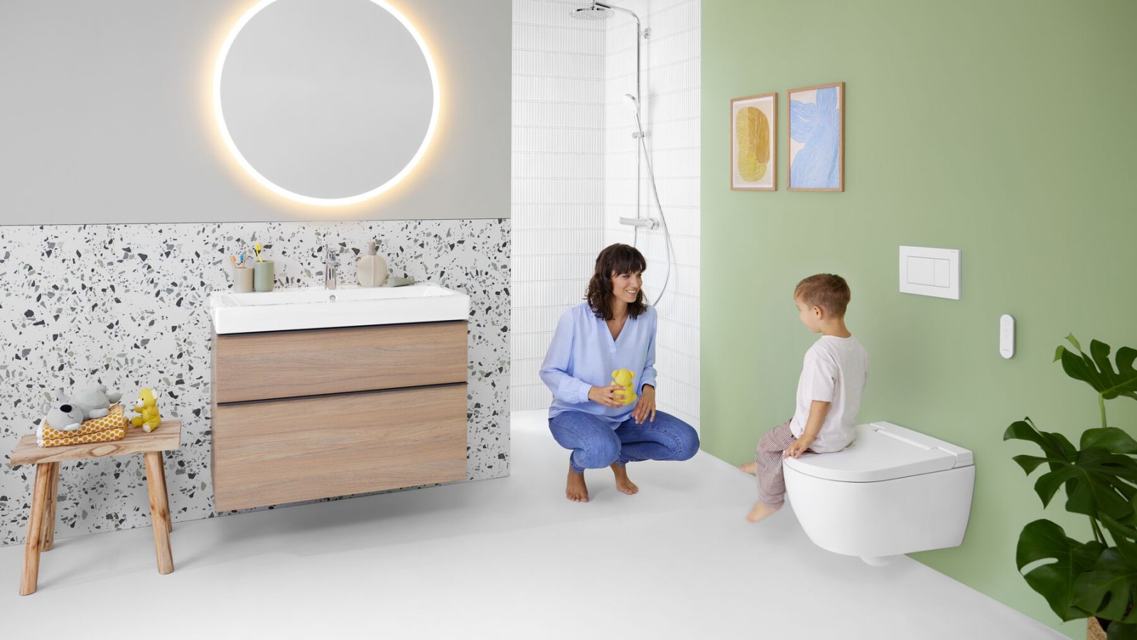 Kvinna och barn i ett badrum med mycket färg och Geberit Option spegel och Geberit AquaClean Alba duschtoalett Kvinna och barn i ett badrum med mycket färg och Geberit Option spegel och Geberit AquaClean Alba duschtoalett